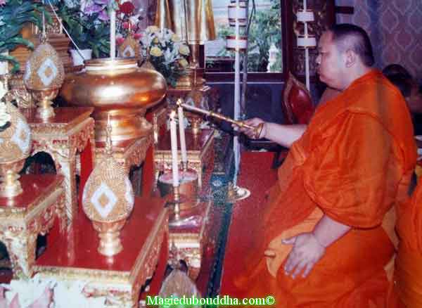 Moine thai qui fait une offrande de lumière au Bouddha.